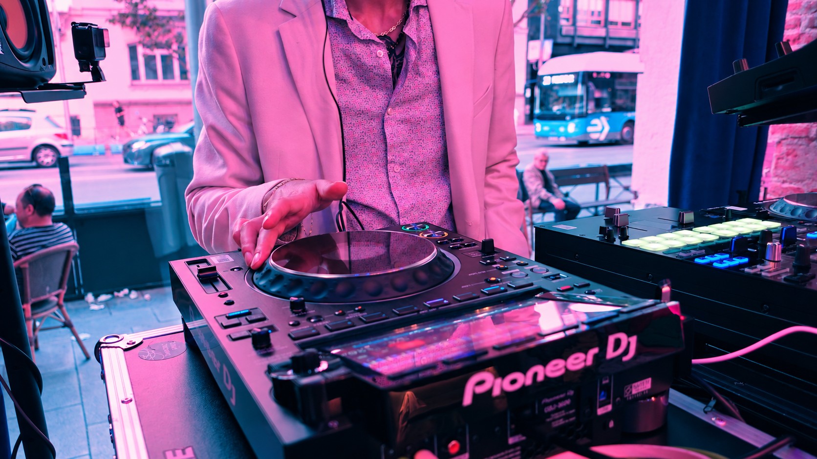 Detalle de un DJ con chaqueta clara mezclando en Sunny Grooves